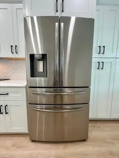 a view of kitchen with stainless steel appliances wooden floor and window