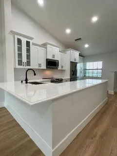 a kitchen with kitchen island granite countertop a sink a stove and cabinets