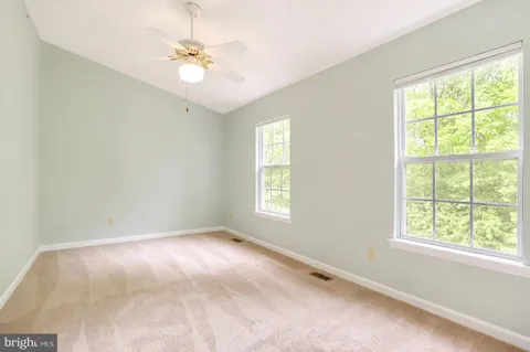 an empty room with windows and ceiling fan
