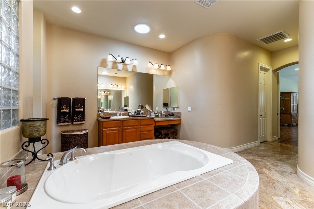 3661 Riley Ann Avenue Las Vegas, NV 89139 - Photo 32 of 42 Indulge in a tranquil bathing experience with this spacious built-in tub, set against warm-toned walls and elegant tile flooring.