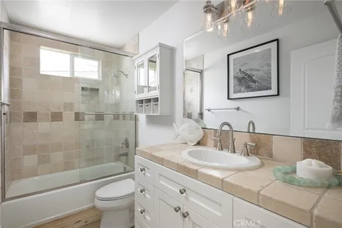 a bathroom with a granite countertop sink a toilet a mirror and shower