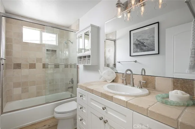 a bathroom with a granite countertop sink a toilet a mirror and shower