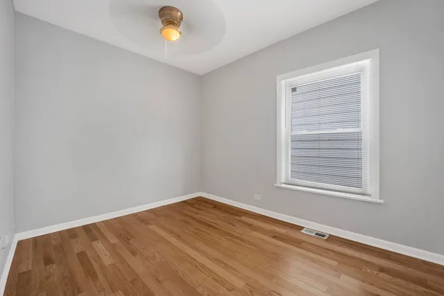 a view of empty room with window and wooden floor