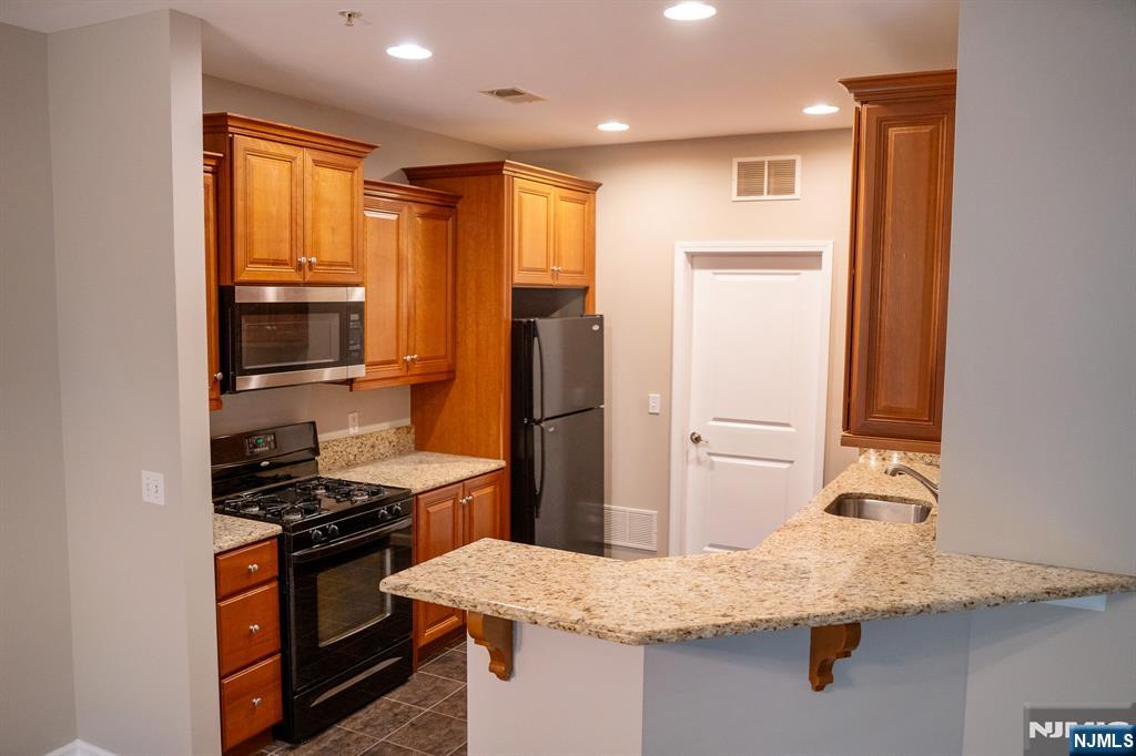 804 River Place Butler, NJ 07405 - Photo 11 of 32 a kitchen with stainless steel appliances granite countertop a sink stove and refrigerator