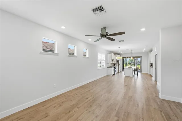 a kitchen with stainless steel appliances a stove a sink a refrigerator and white cabinets with wooden floor