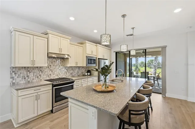 a kitchen with stainless steel appliances granite countertop a sink a refrigerator and a wooden floor
