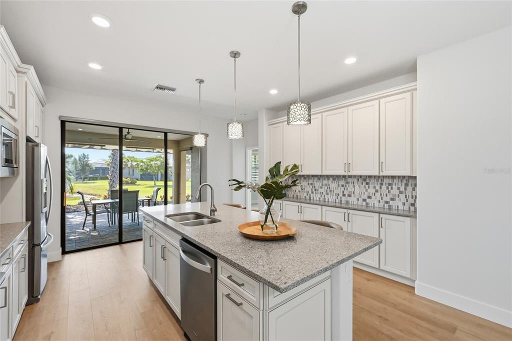 17029 Hampton Falls Terrace Lakewood Ranch, FL 34202 - Photo 18 of 56 a kitchen with kitchen island a large counter top space a sink stainless steel appliances and cabinets