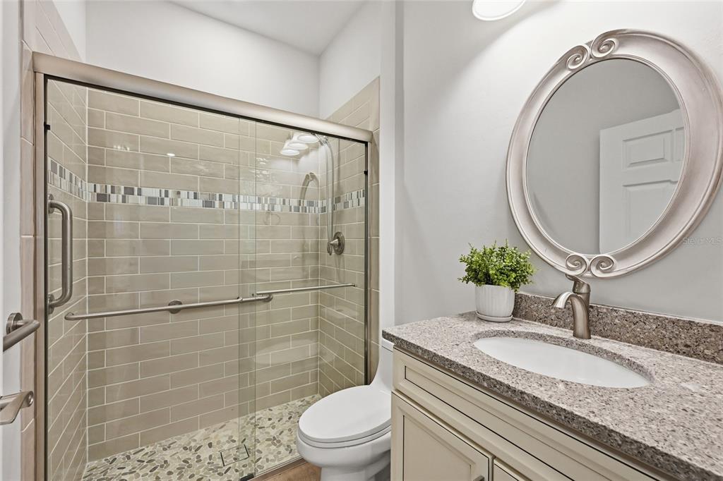 17029 Hampton Falls Terrace Lakewood Ranch, FL 34202 - Photo 33 of 56 a bathroom with a granite countertop sink a mirror a toilet and shower