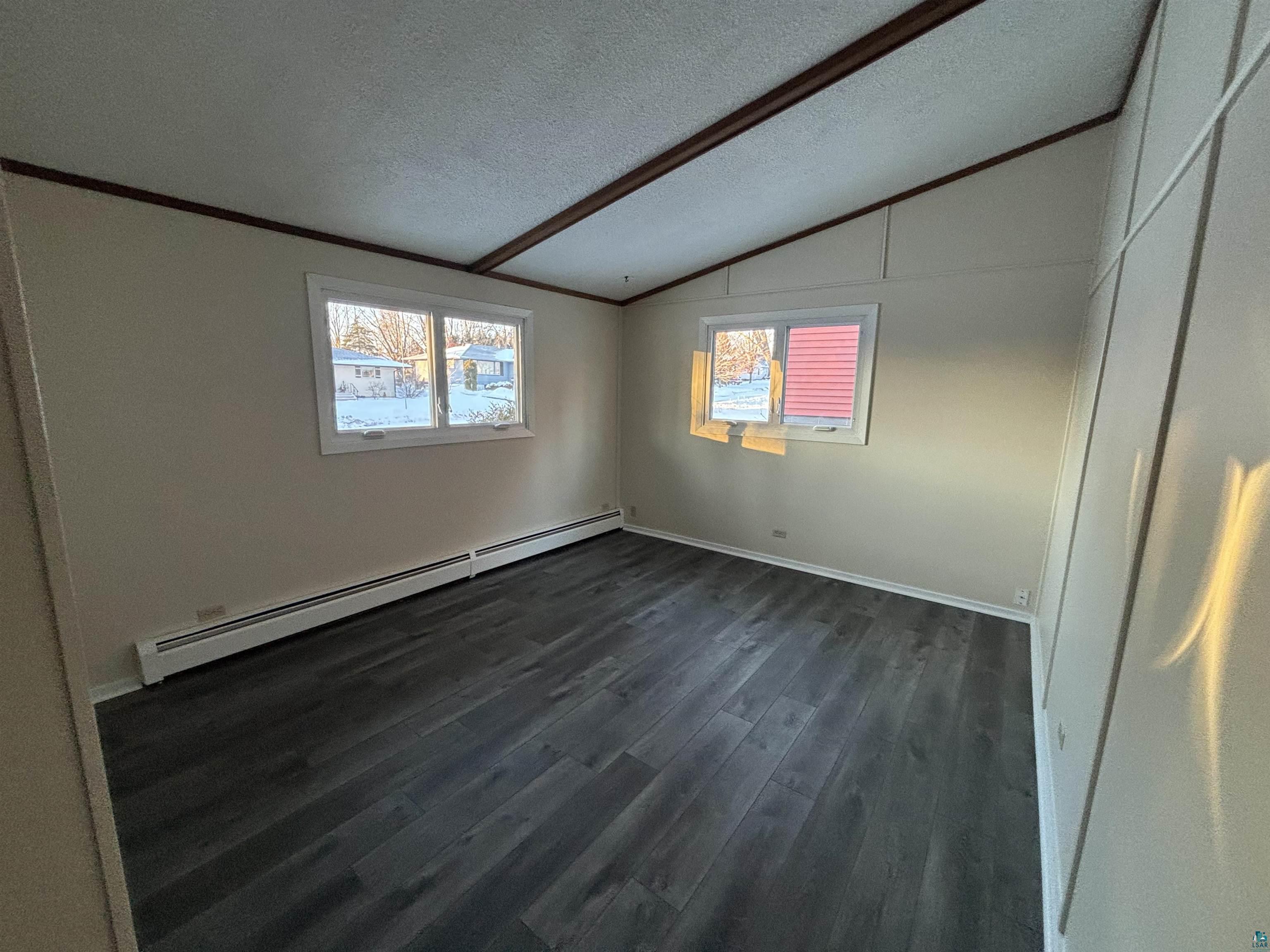 4919 Oakley Street Duluth, MN 55804 - Photo 15 of 20 Empty room featuring a textured ceiling, dark wood finished floors, a baseboard radiator, and lofted ceiling
