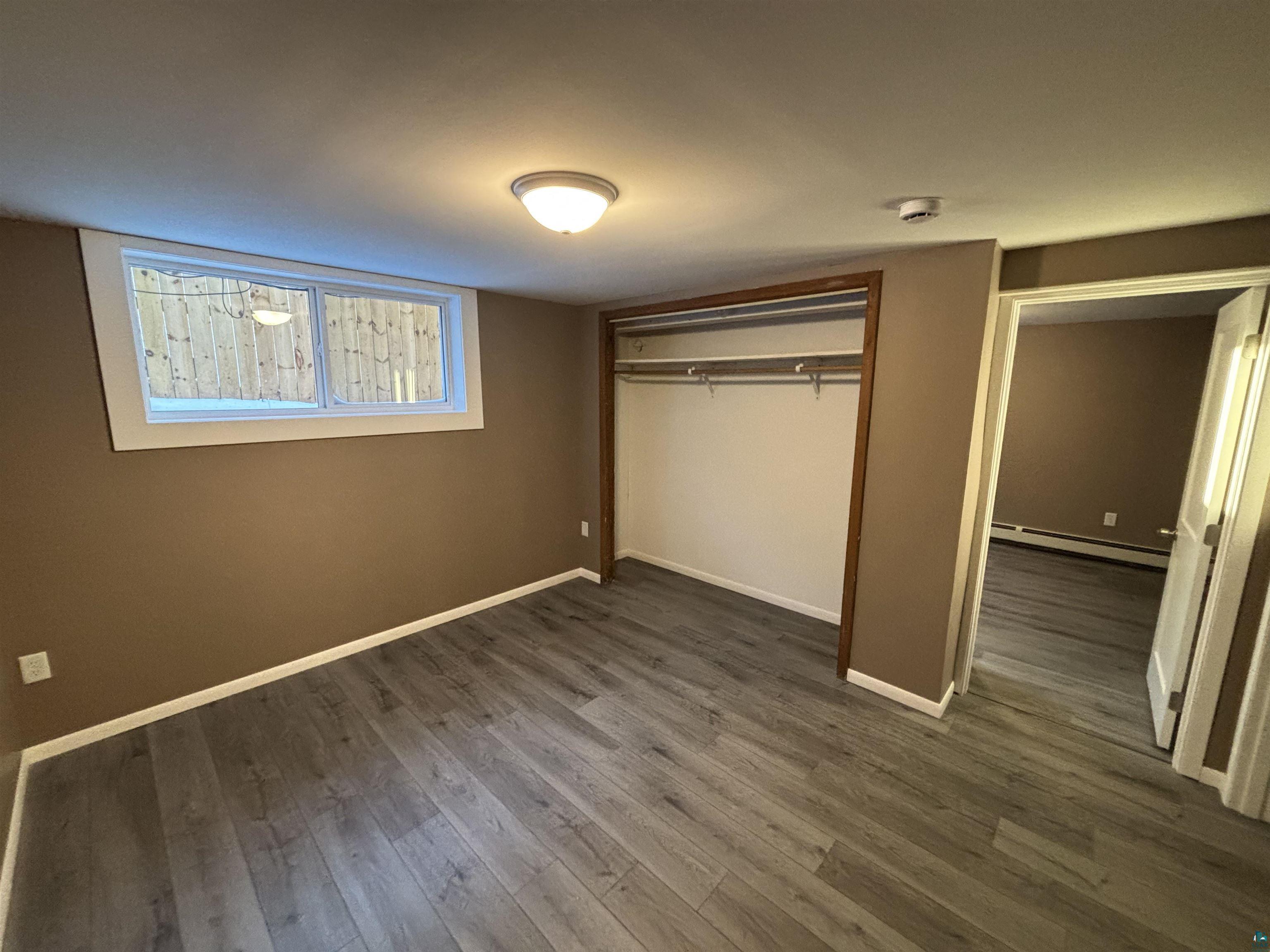 4919 Oakley Street Duluth, MN 55804 - Photo 17 of 20 Unfurnished bedroom with a closet, dark wood-style floors, and a baseboard heating unit