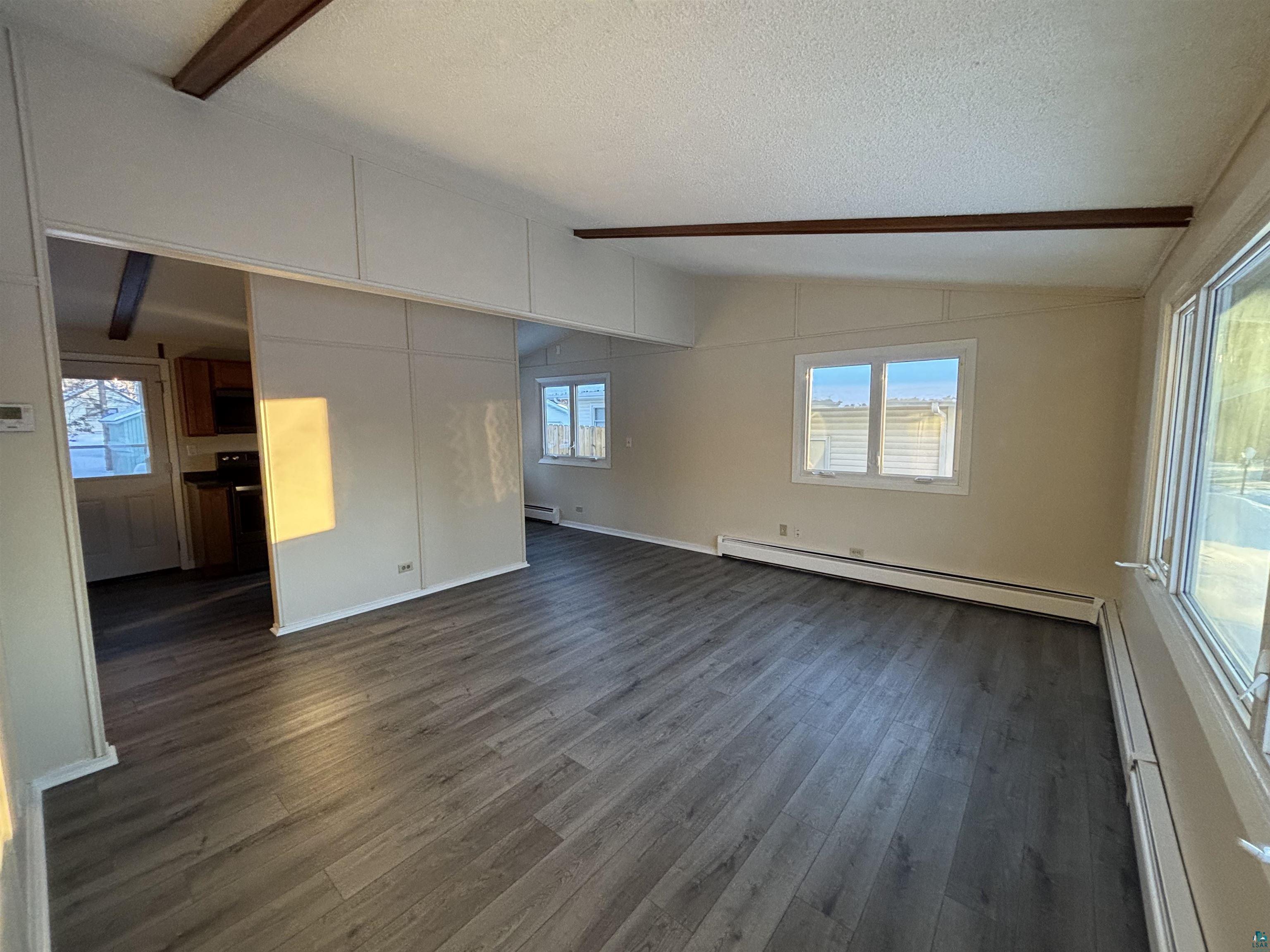 4919 Oakley Street Duluth, MN 55804 - Photo 4 of 20 Spare room featuring baseboard heating, dark wood-type flooring, and a textured ceiling