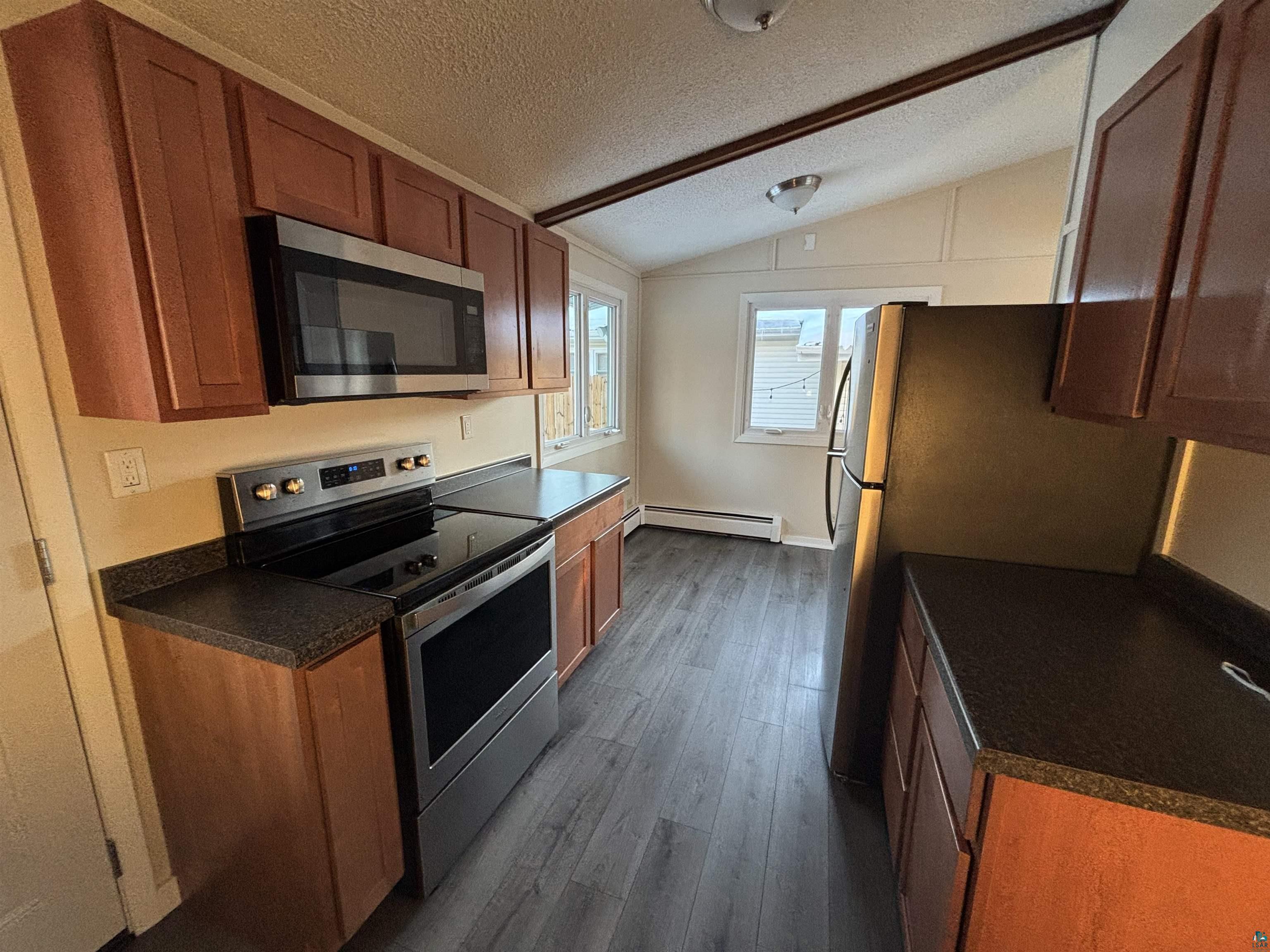4919 Oakley Street Duluth, MN 55804 - Photo 7 of 20 Kitchen featuring dark countertops, stainless steel appliances, vaulted ceiling, a textured ceiling, and brown cabinets