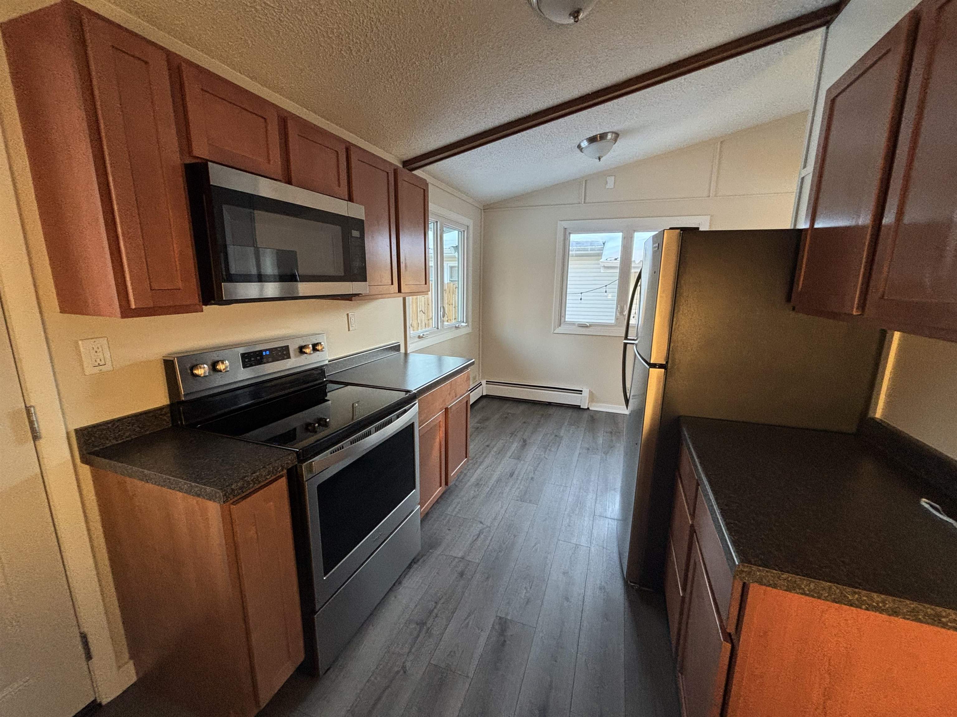 4919 Oakley Street Duluth, MN 55804 - Photo 7 of 20 Kitchen featuring dark countertops, stainless steel appliances, vaulted ceiling, a textured ceiling, and brown cabinets