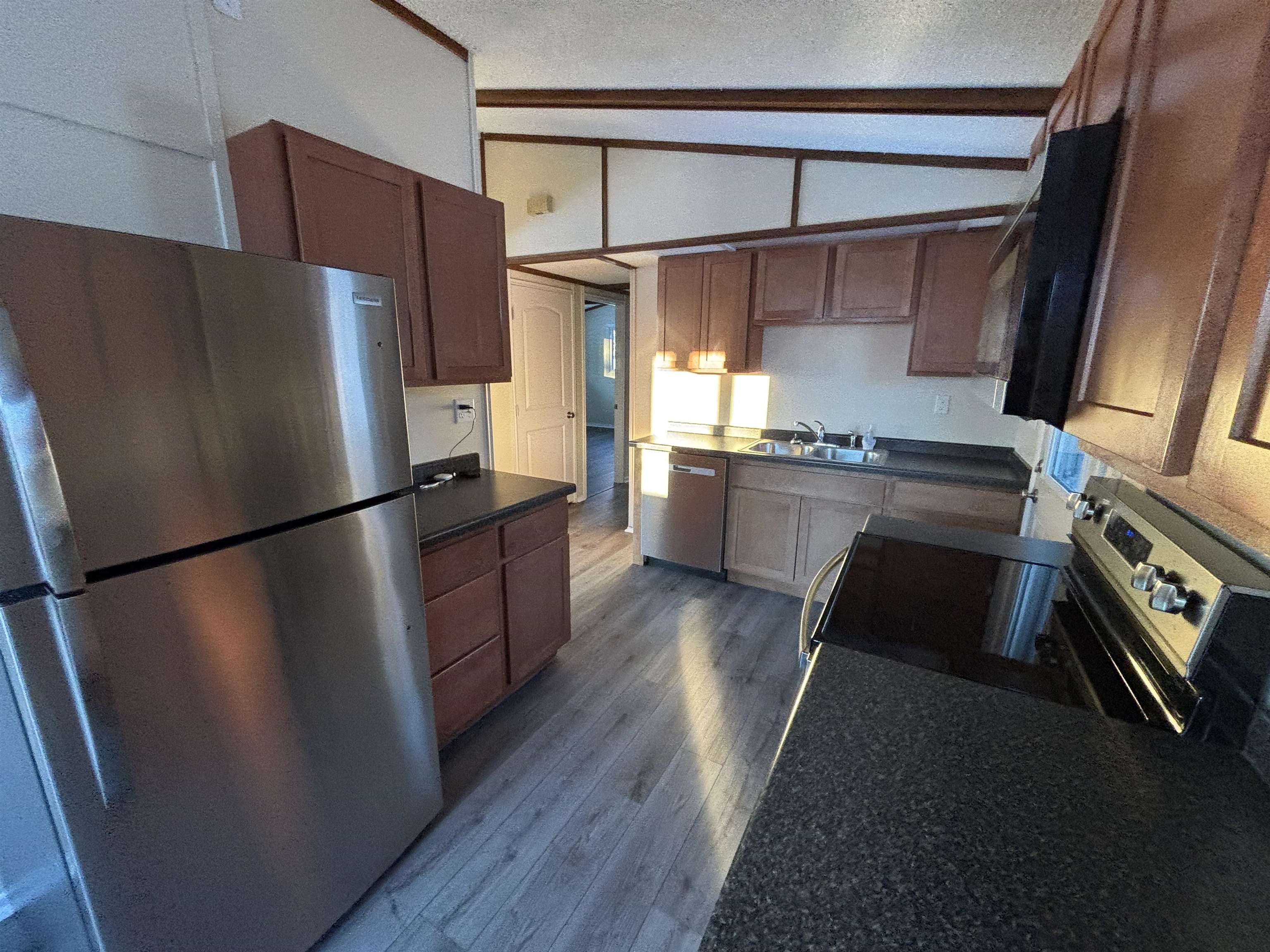 4919 Oakley Street Duluth, MN 55804 - Photo 10 of 20 Kitchen with dark countertops, stainless steel appliances, vaulted ceiling, and dark wood finished floors