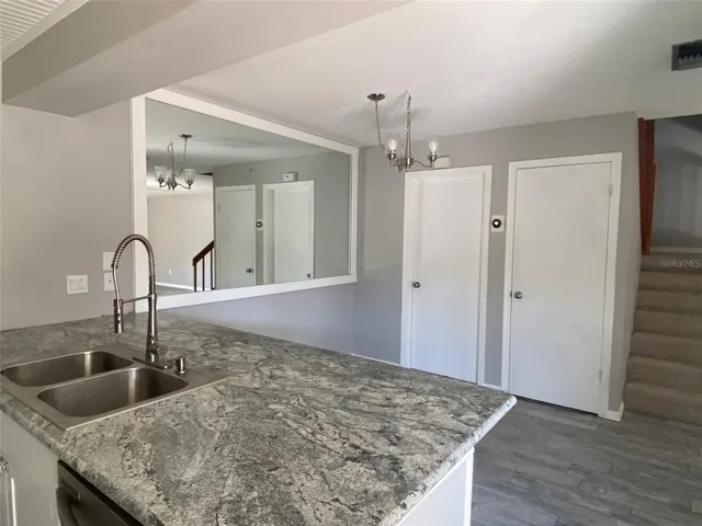 a kitchen with granite countertop a sink a refrigerator and chandelier