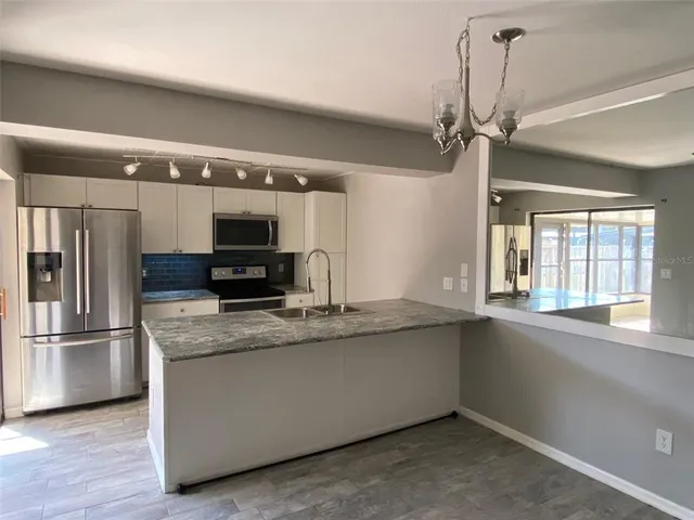 a kitchen with stainless steel appliances granite countertop a refrigerator a sink and a stove