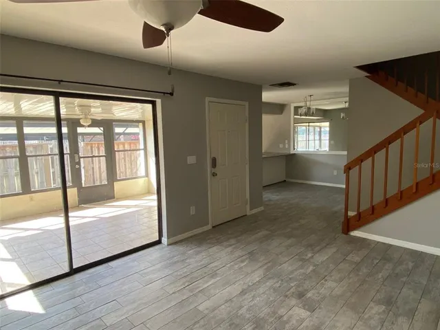 a view of an empty room with wooden floor and windows