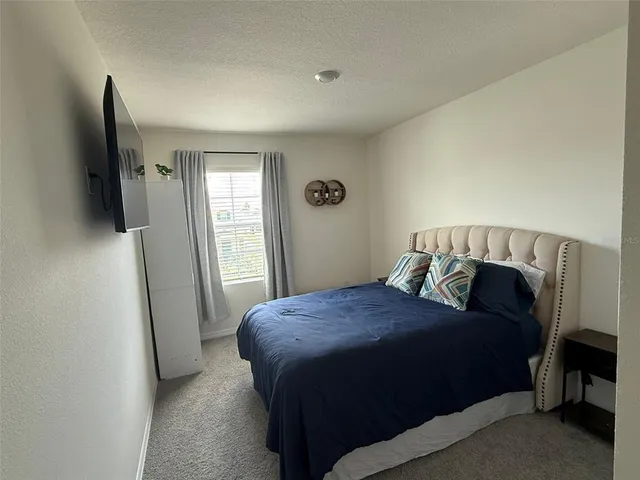 a bedroom with a bed and a flat tv screen on a dresser