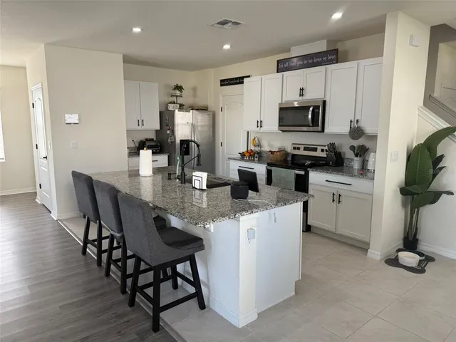 a kitchen with stainless steel appliances kitchen island granite countertop a table chairs microwave and sink
