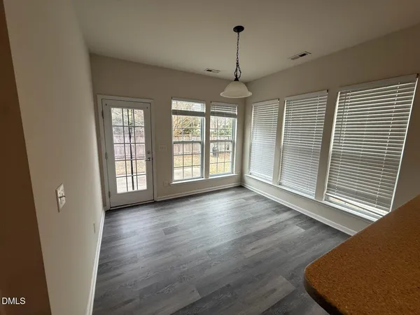 an empty room with wooden floor windows and glass door