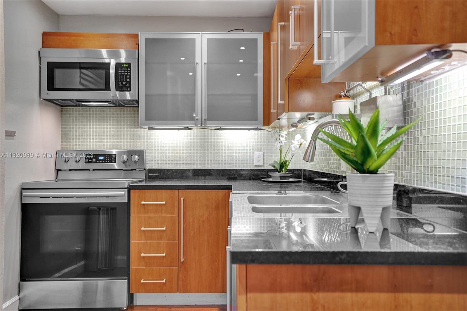 200 Southeast 15th Road, Unit 6I Miami, FL 33129 - Photo 8 of 50 a kitchen with stainless steel appliances granite countertop a sink a stove and a microwave oven
