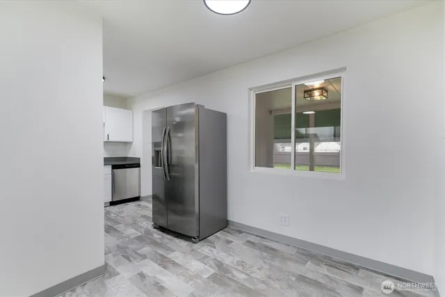 a view of a refrigerator in kitchen and an empty room