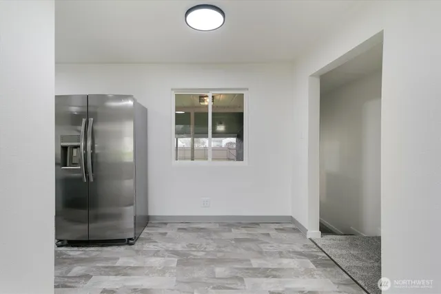 a view of a refrigerator in kitchen and empty room