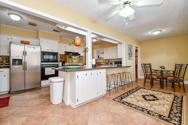a kitchen with stainless steel appliances kitchen island granite countertop a refrigerator a stove a microwave oven with a dining table and chairs