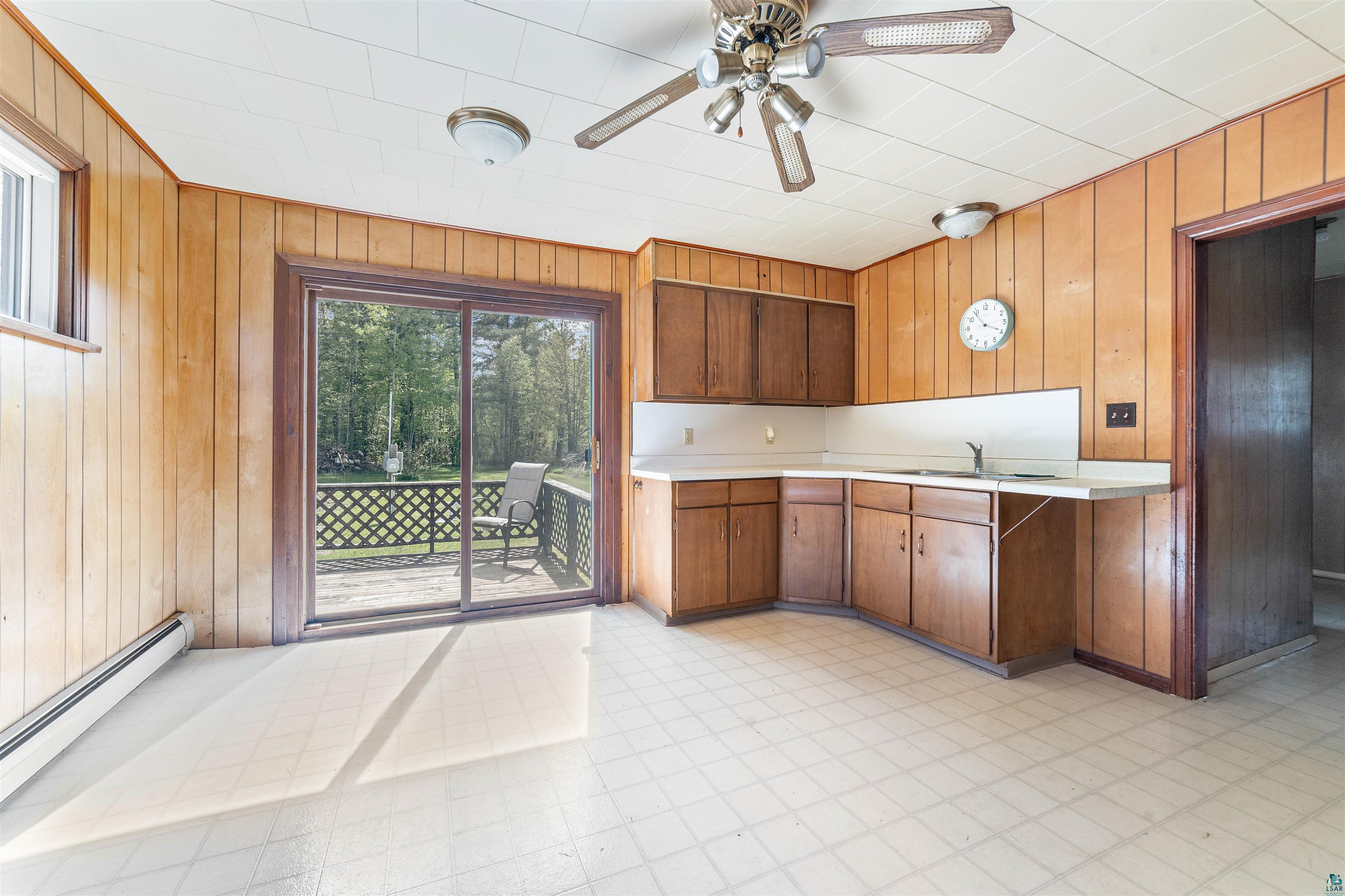 3469 County Road East South Range, WI 54874 - Photo 3 of 19 Kitchen with ceiling fan, light tile floors, a baseboard heating unit, wooden walls, and sink