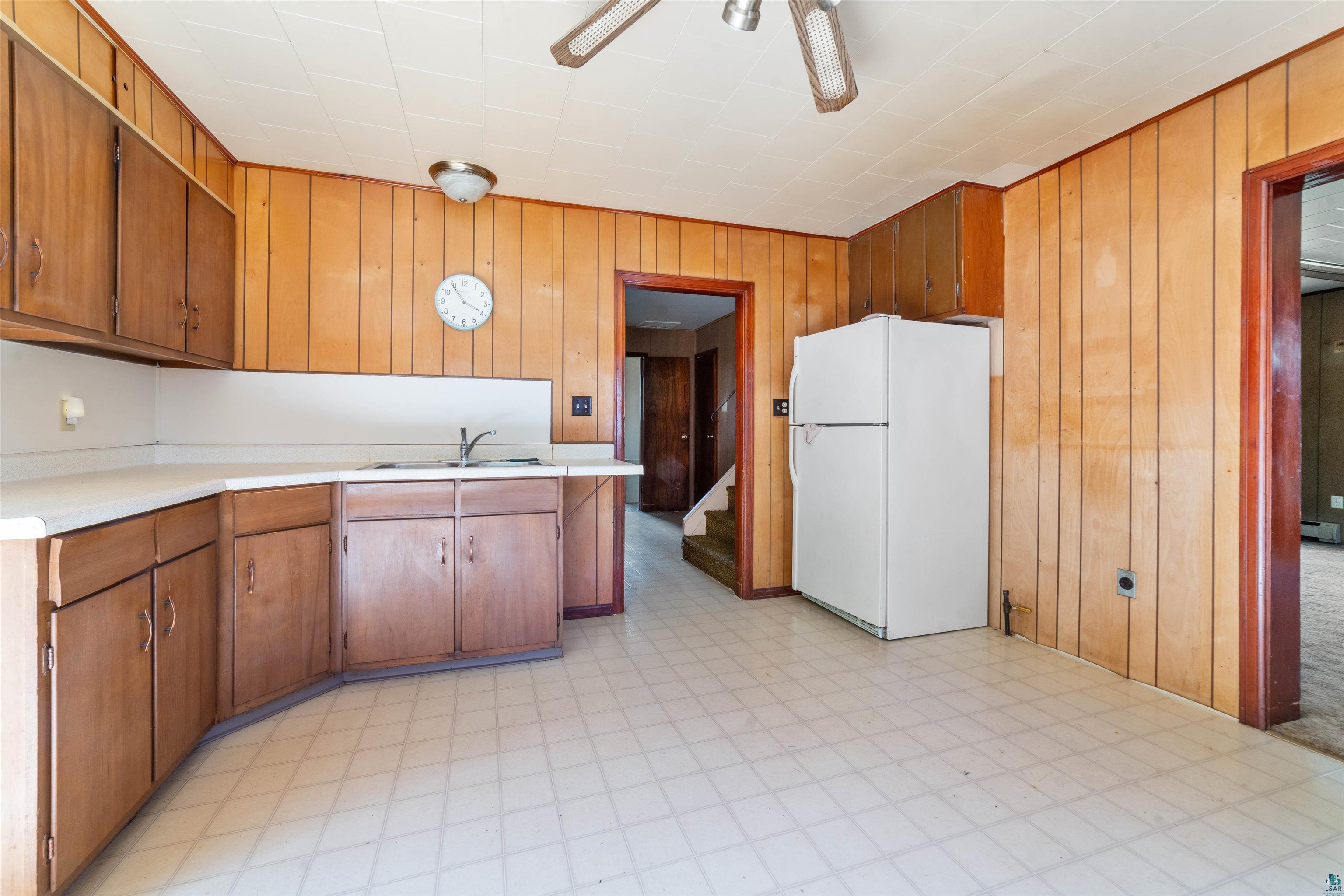 3469 County Road East South Range, WI 54874 - Photo 4 of 19 Kitchen with ceiling fan, sink, white refrigerator, and wood walls