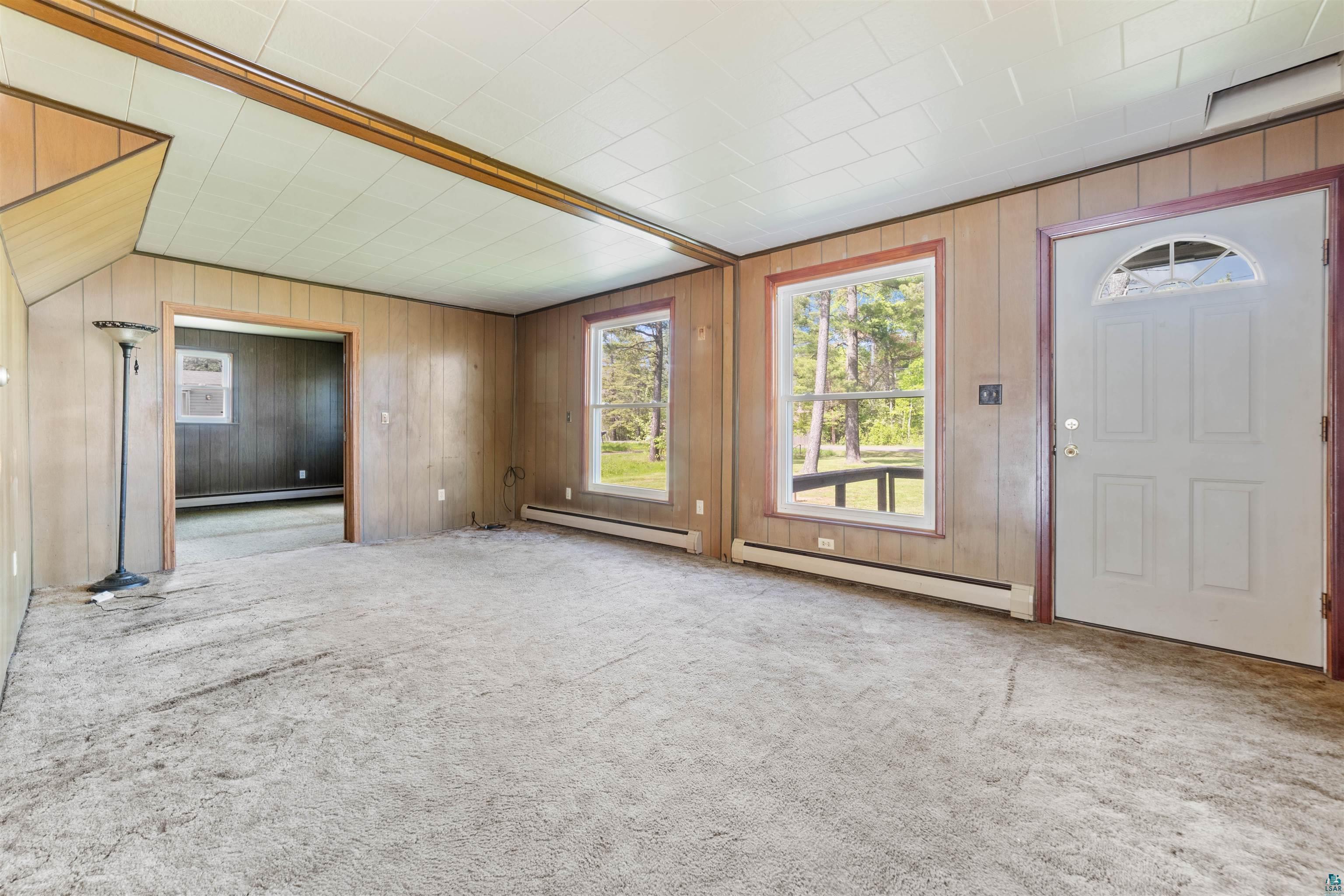 3469 County Road East South Range, WI 54874 - Photo 5 of 19 Unfurnished living room featuring a baseboard radiator, carpet floors, and wooden walls