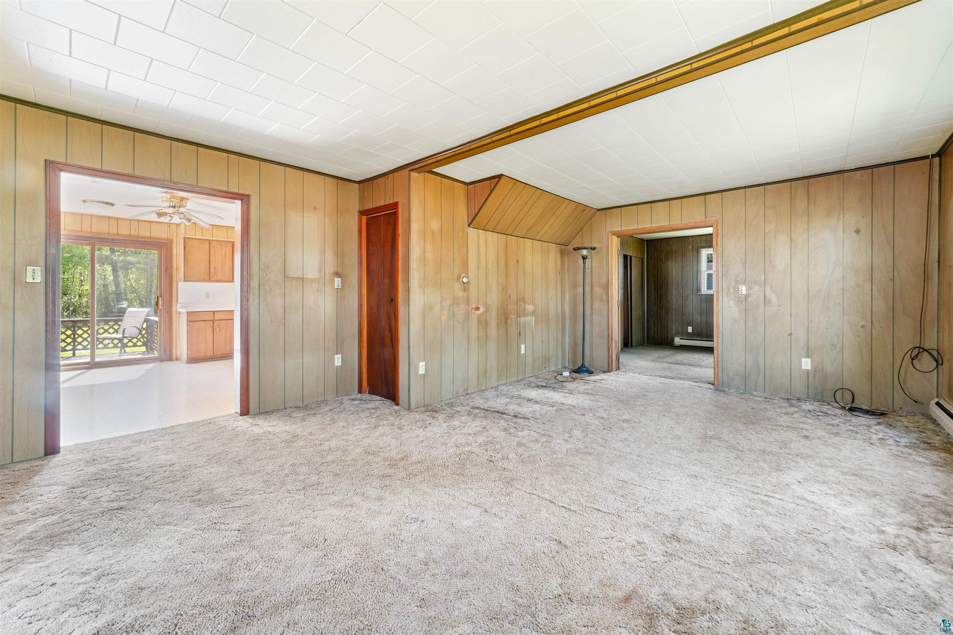 3469 County Road East South Range, WI 54874 - Photo 6 of 19 Empty room featuring a baseboard heating unit, wooden walls, ceiling fan, and carpet floors