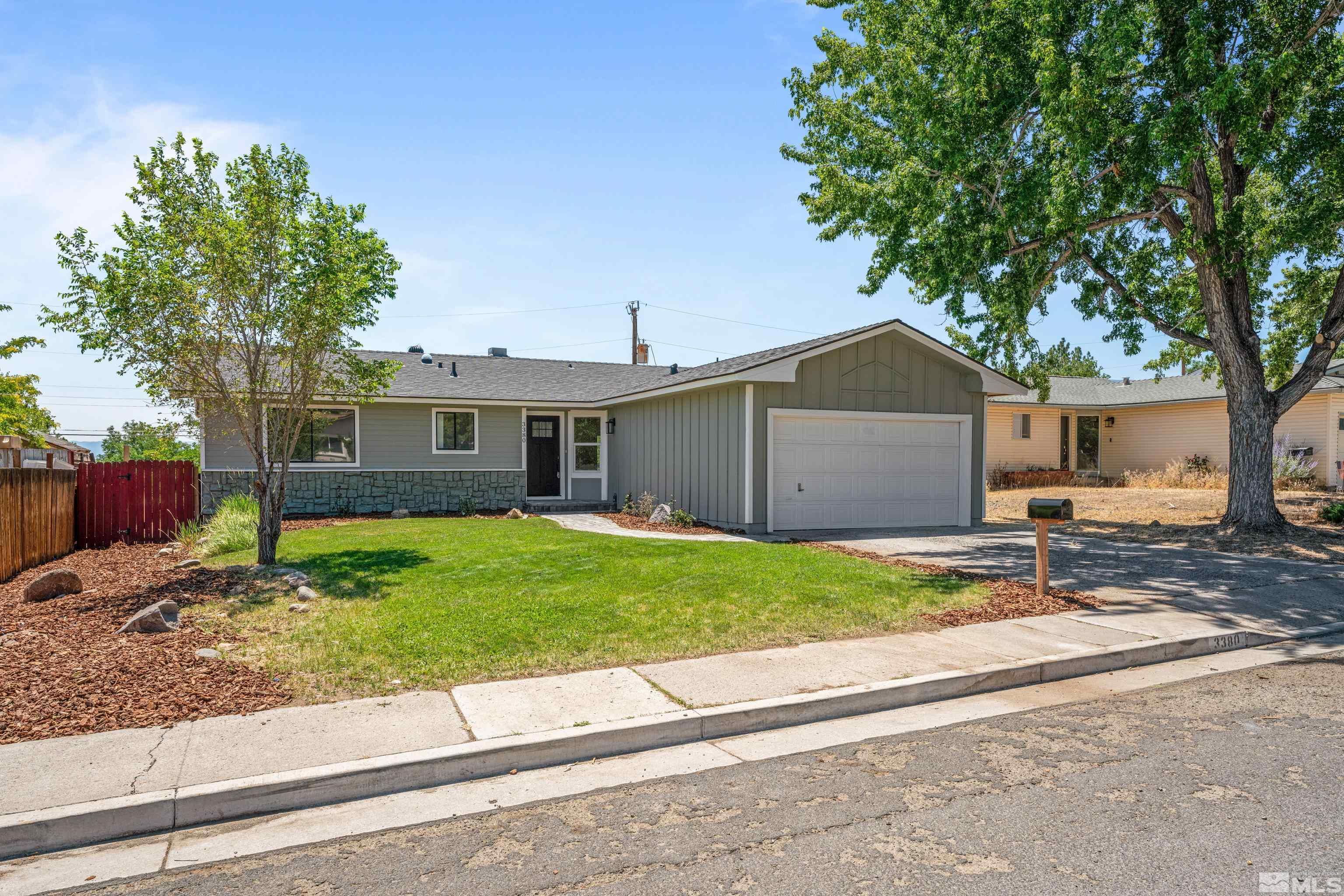 a view of a house with a yard and large tree