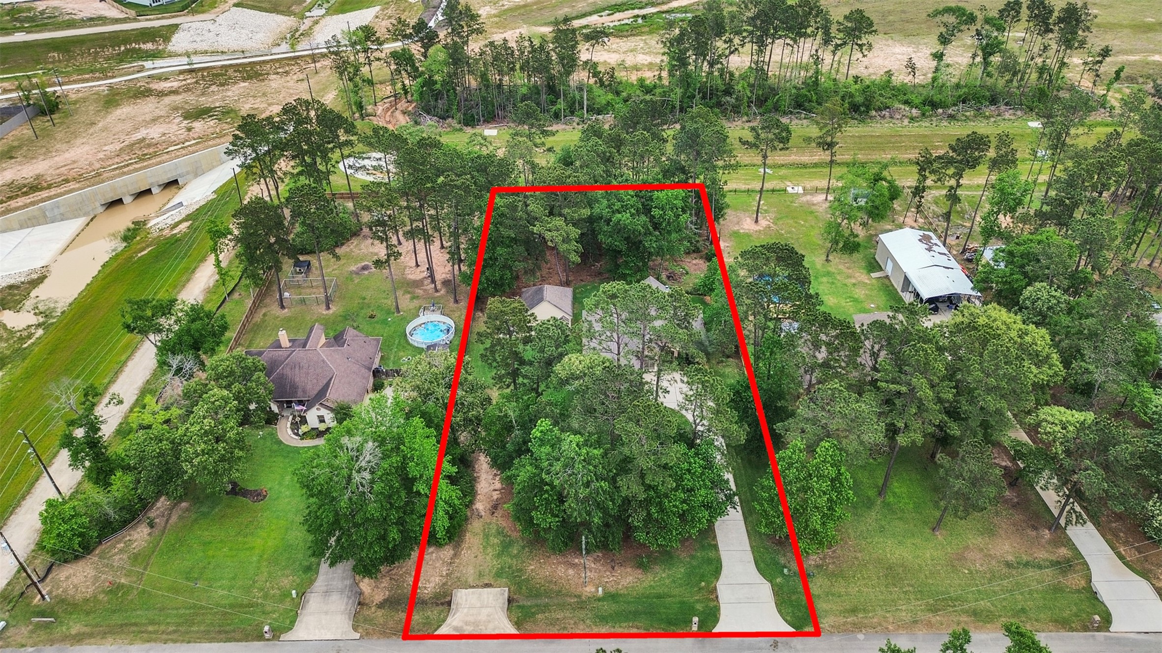 18005 Cindy Lane Conroe, TX 77302 - Photo 4 of 49 This aerial photo shows a wooded property outlined in red, featuring a house nestled among trees. The lot has a driveway leading to the house, providing a sense of privacy and natural surroundings. Extra Parking.