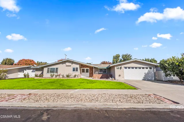 a front view of house with garden and trees in the background