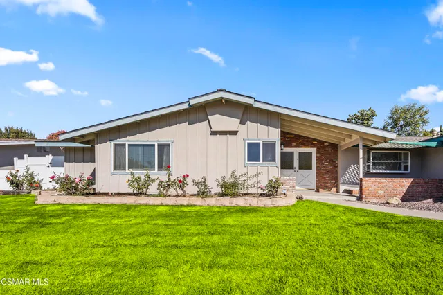 a view of house that has a big yard with large trees