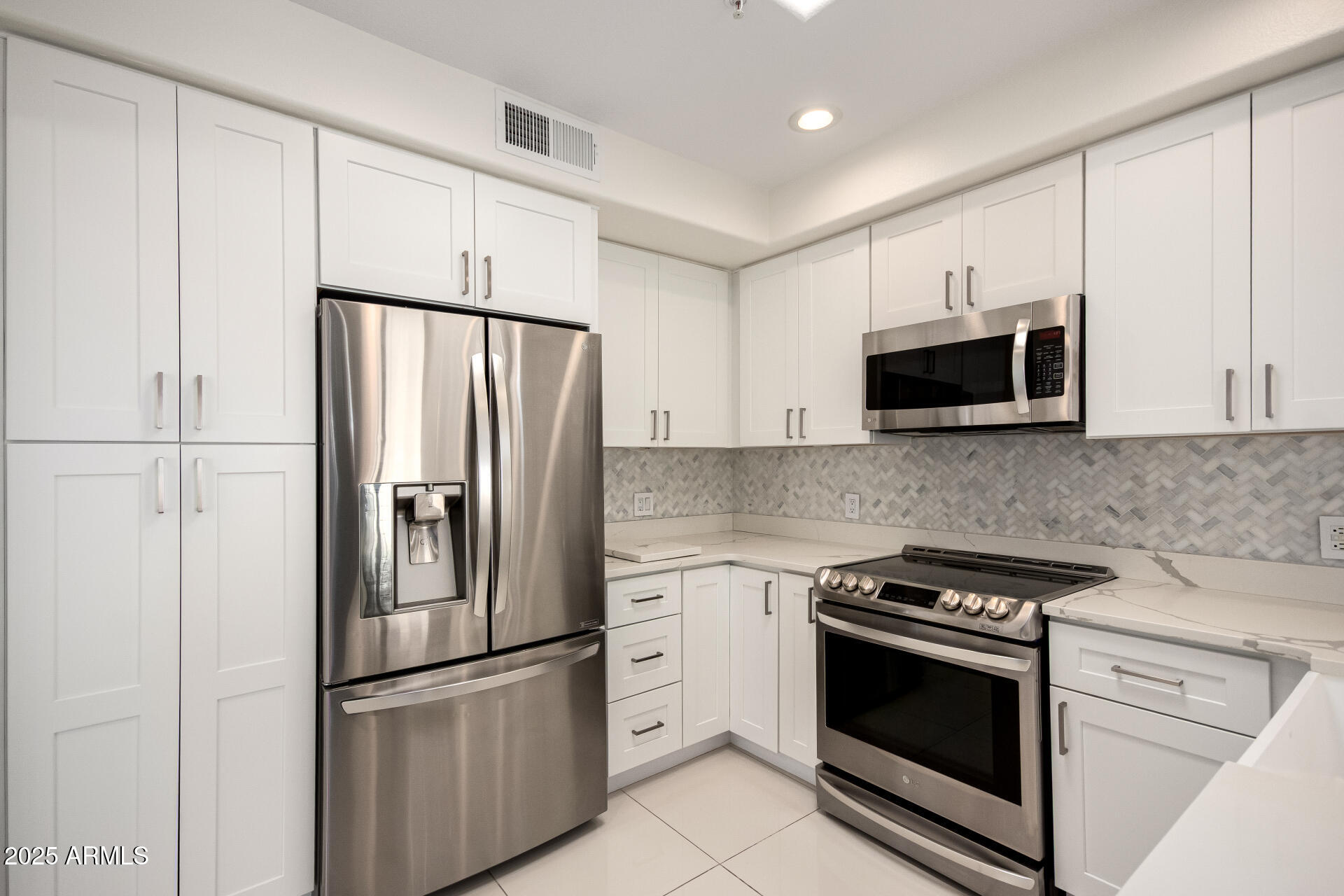 7222 East Gainey Ranch Road, Unit 241 Scottsdale, AZ 85258 - Photo 3 of 74 a kitchen with stainless steel appliances white cabinets and a stove top oven
