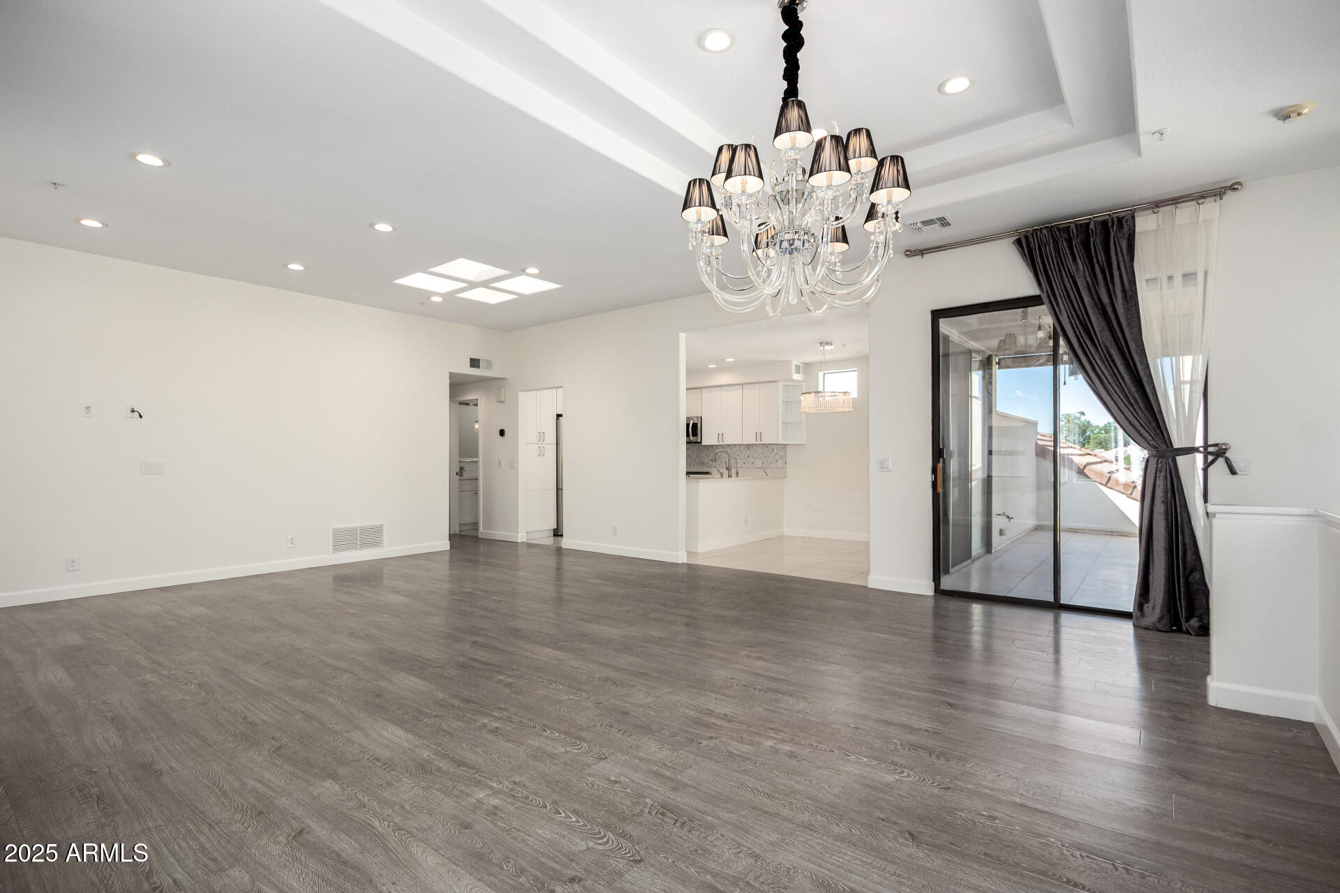 7222 East Gainey Ranch Road, Unit 241 Scottsdale, AZ 85258 - Photo 37 of 74 a view of an empty room with wooden floor and a kitchen
