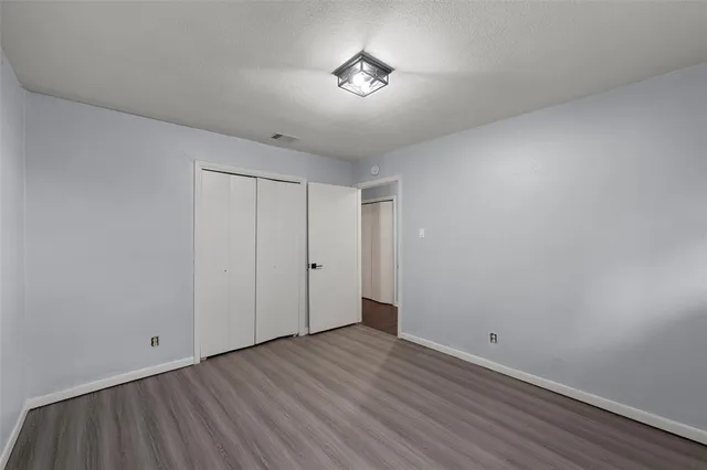a view of an empty room with wooden floor and a ceiling fan
