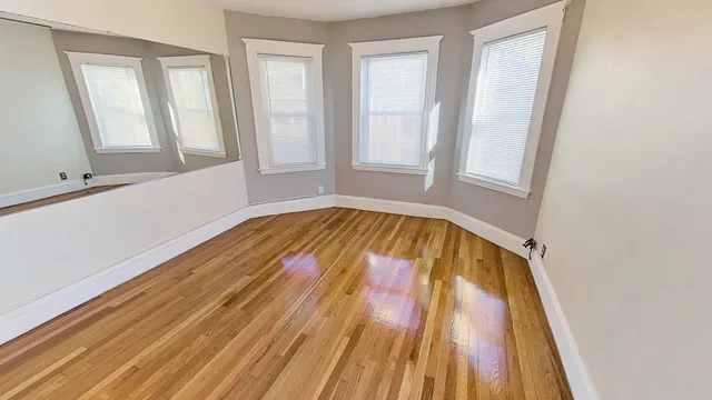 a view of an empty room with wooden floor and a window