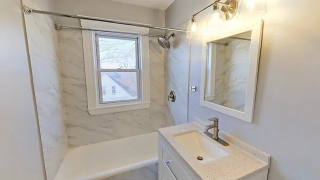 a bathroom with a tub sink vanity and mirror