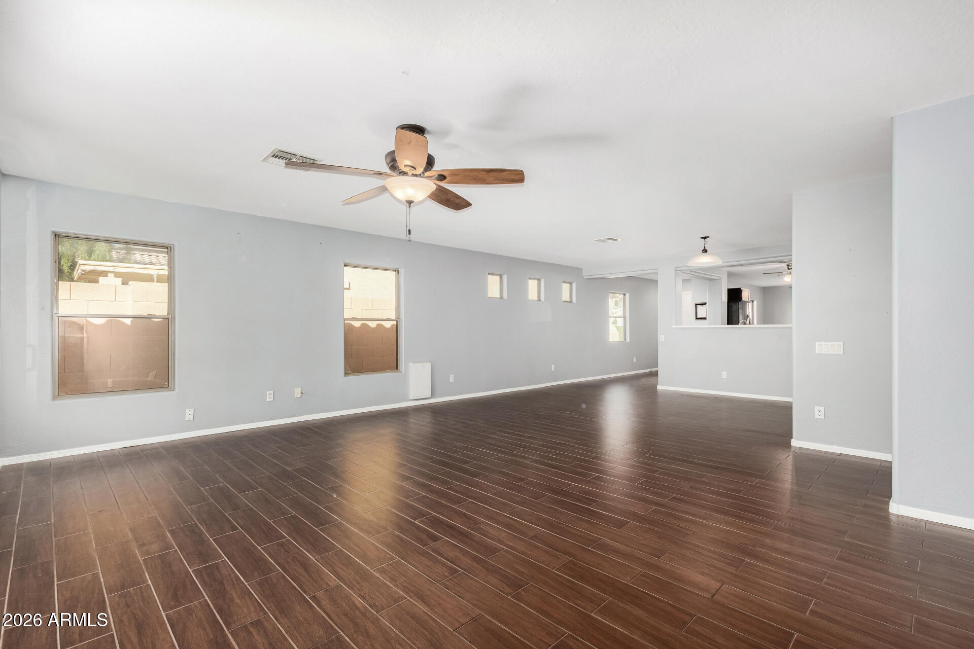 43845 West Elizabeth Avenue Maricopa, AZ 85138 - Photo 5 of 30 a view of an empty room with window and wooden floor