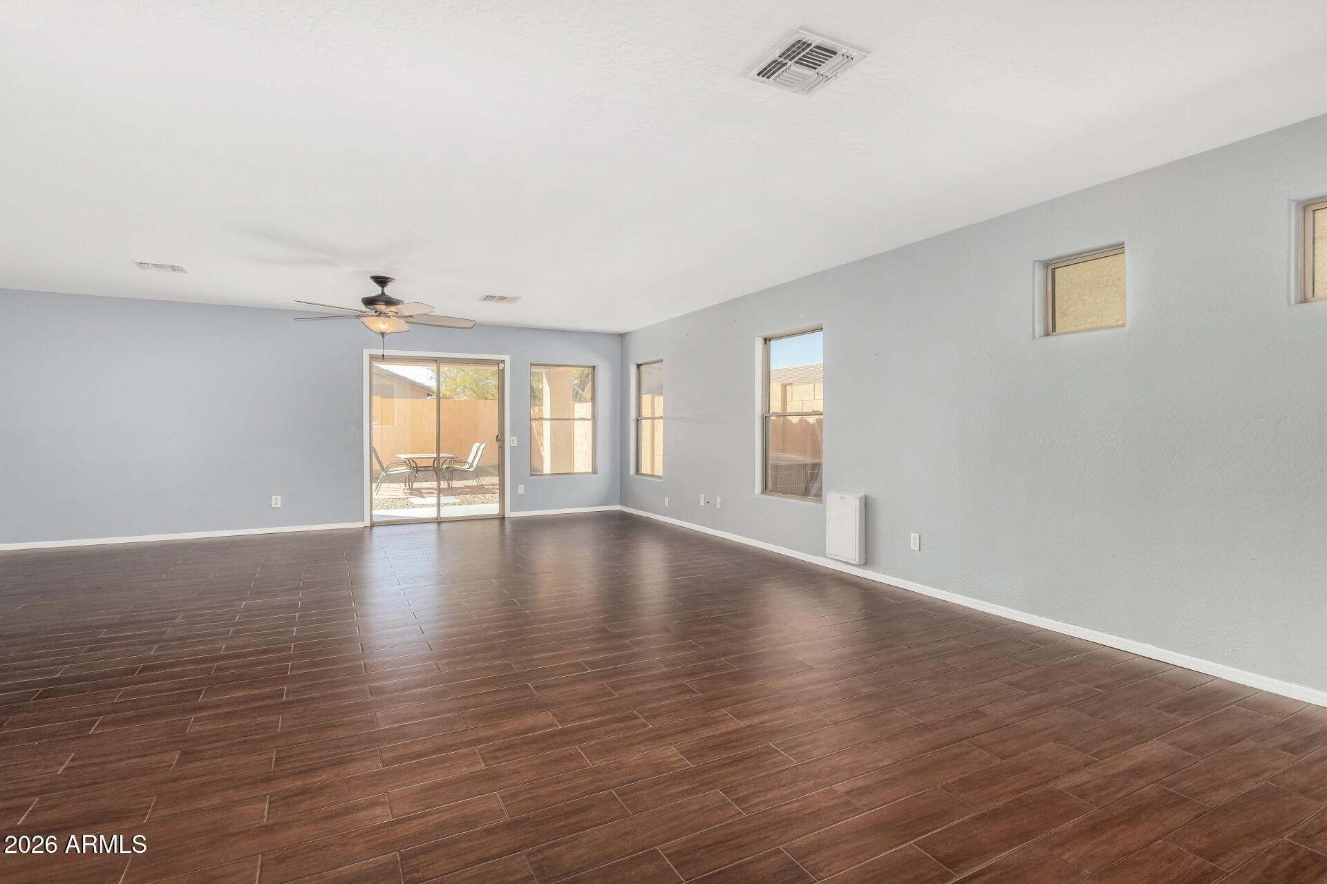 43845 West Elizabeth Avenue Maricopa, AZ 85138 - Photo 7 of 30 a view of an empty room with window and wooden floor