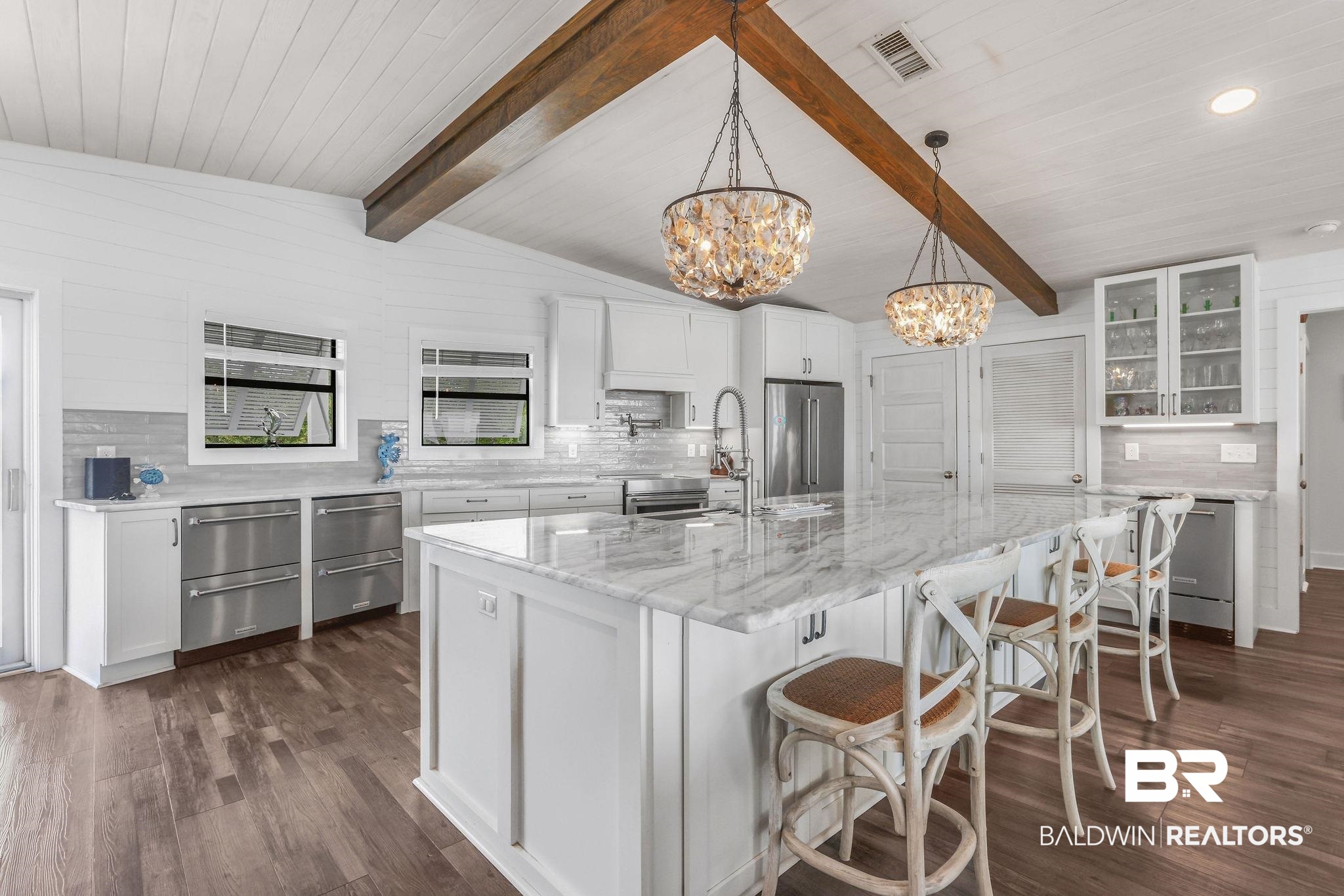 32130 River Road Orange Beach, AL 36561 - Photo 8 of 51 Kitchen with backsplash, white cabinetry, glass insert cabinets, and a kitchen bar