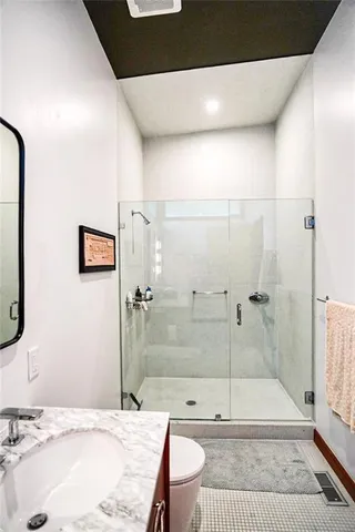 a bathroom with a granite countertop sink a toilet and shower