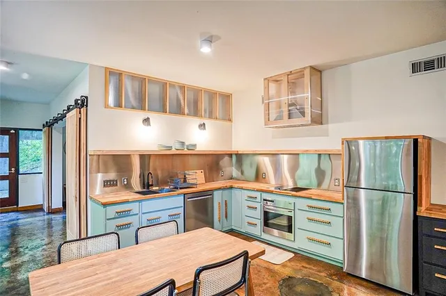 a kitchen with stainless steel appliances granite countertop a refrigerator and a stove top oven