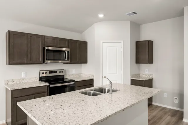 a kitchen with granite countertop stainless steel appliances a sink microwave and stove