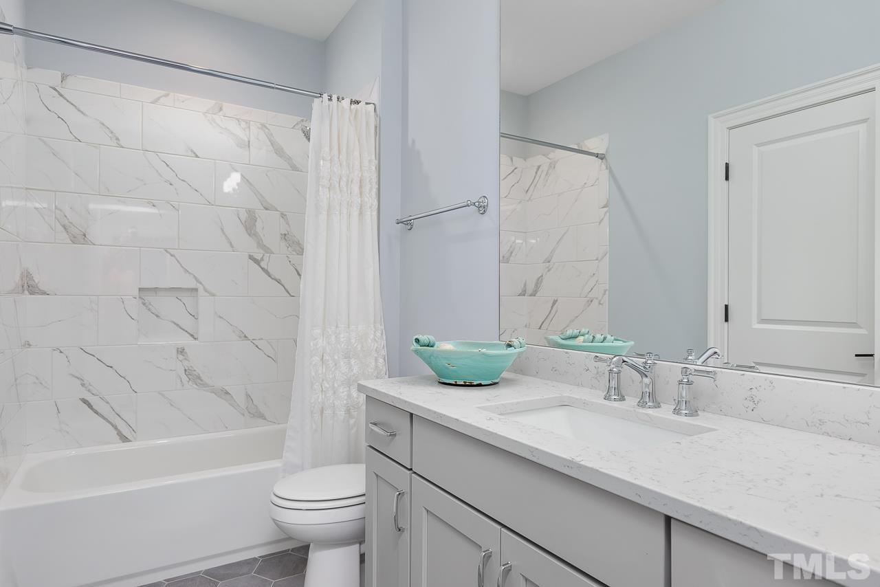 1709 Montvale Grant Way Apex, NC 27523 - Photo 40 of 68 a bathroom with a granite countertop sink a toilet and a bathtub