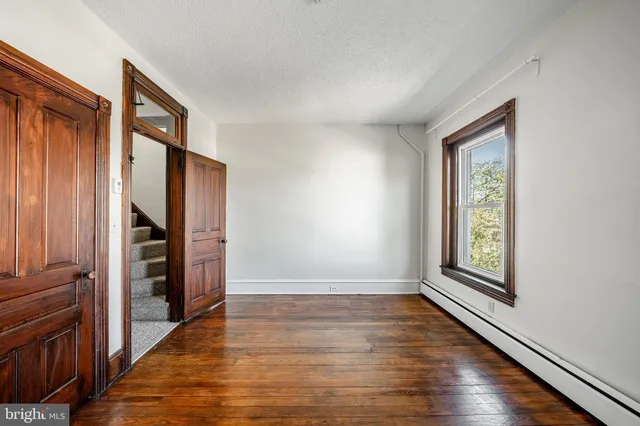 an empty room with wooden floor closet and windows