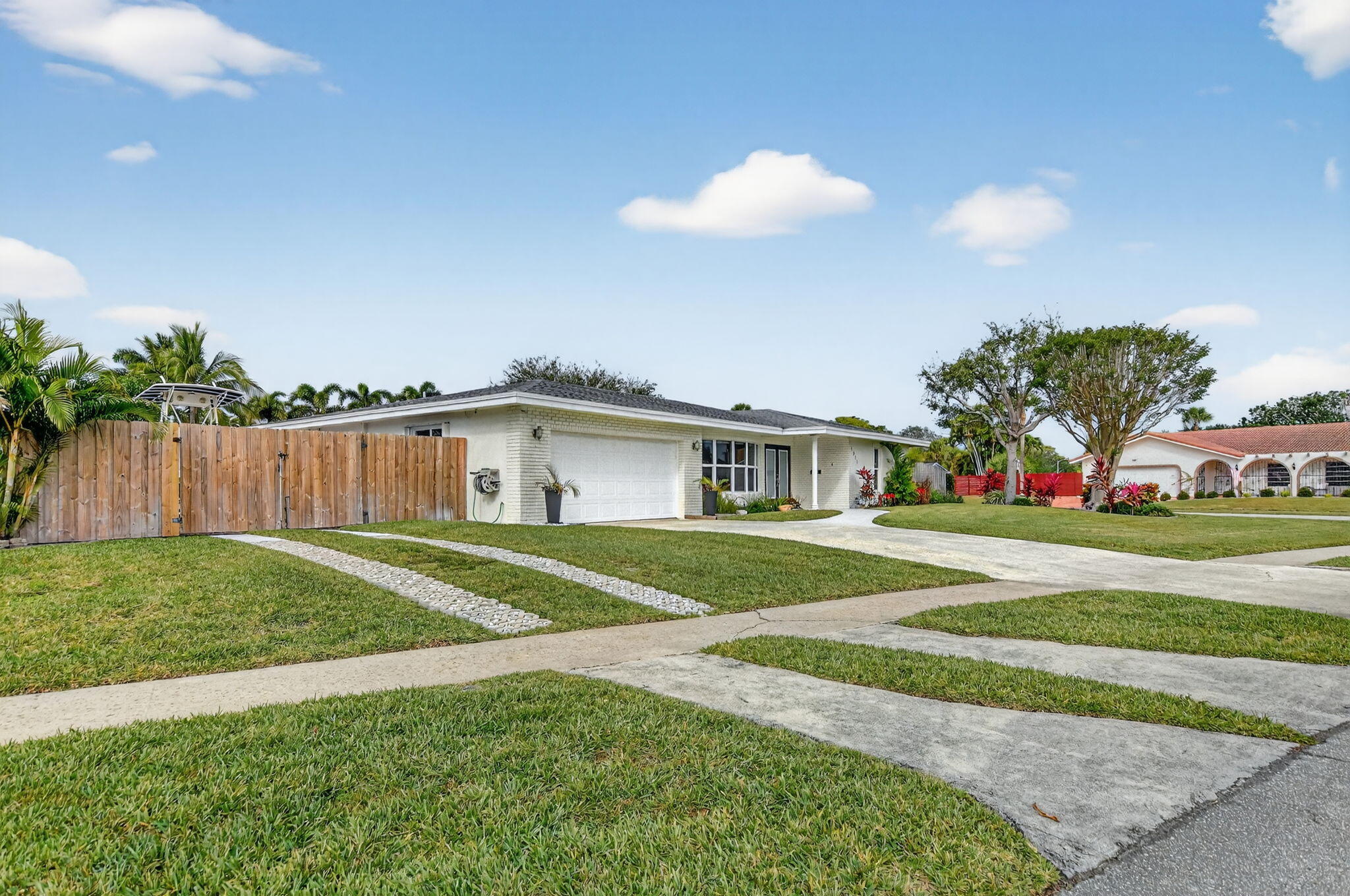 1311 Southwest 14th Avenue Boca Raton, FL 33486 - Photo 47 of 54 a front view of a house with a yard and garage